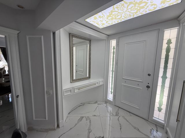 Beyaz antrede duvara asılı konsol, ayna ve panel detayları